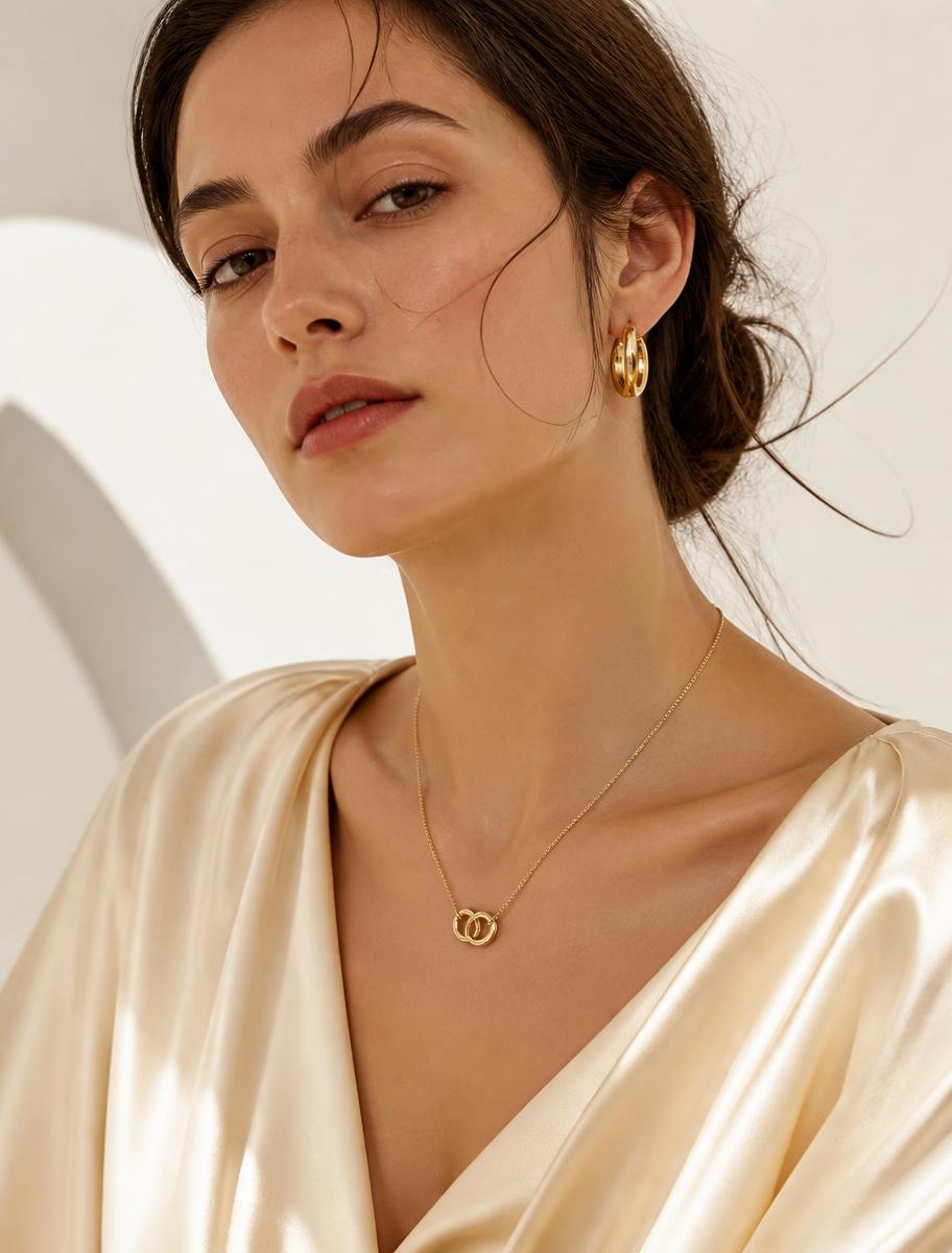 Model wearing gold hoop earrings and a fine layered necklace